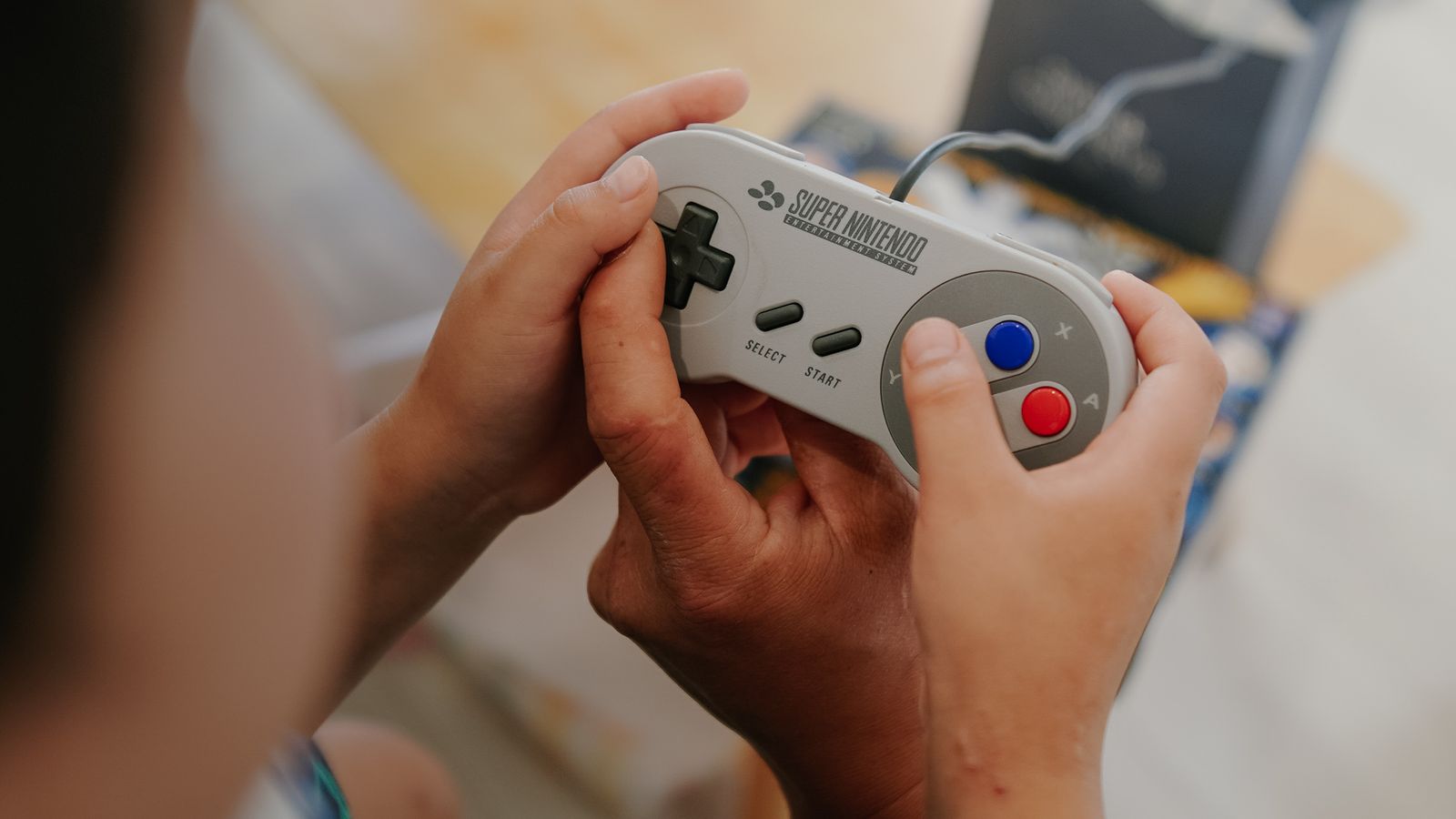 Mains tenant une manette de jeu vidéo rétro.