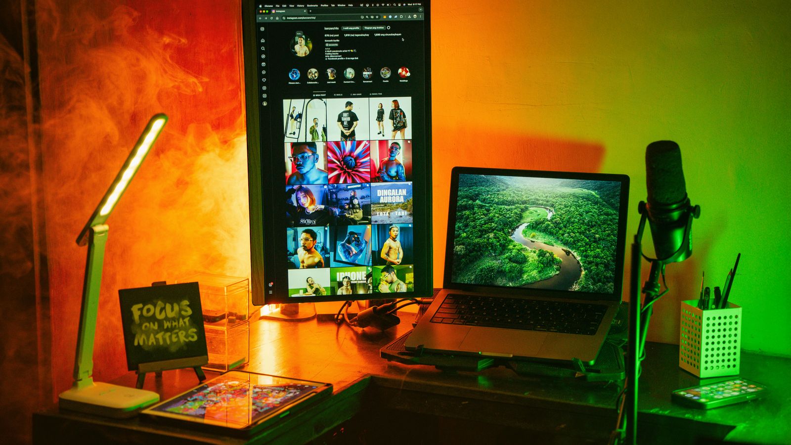 Bureau à domicile coloré avec plusieurs écrans et éclairage d'ambiance orange et vert.