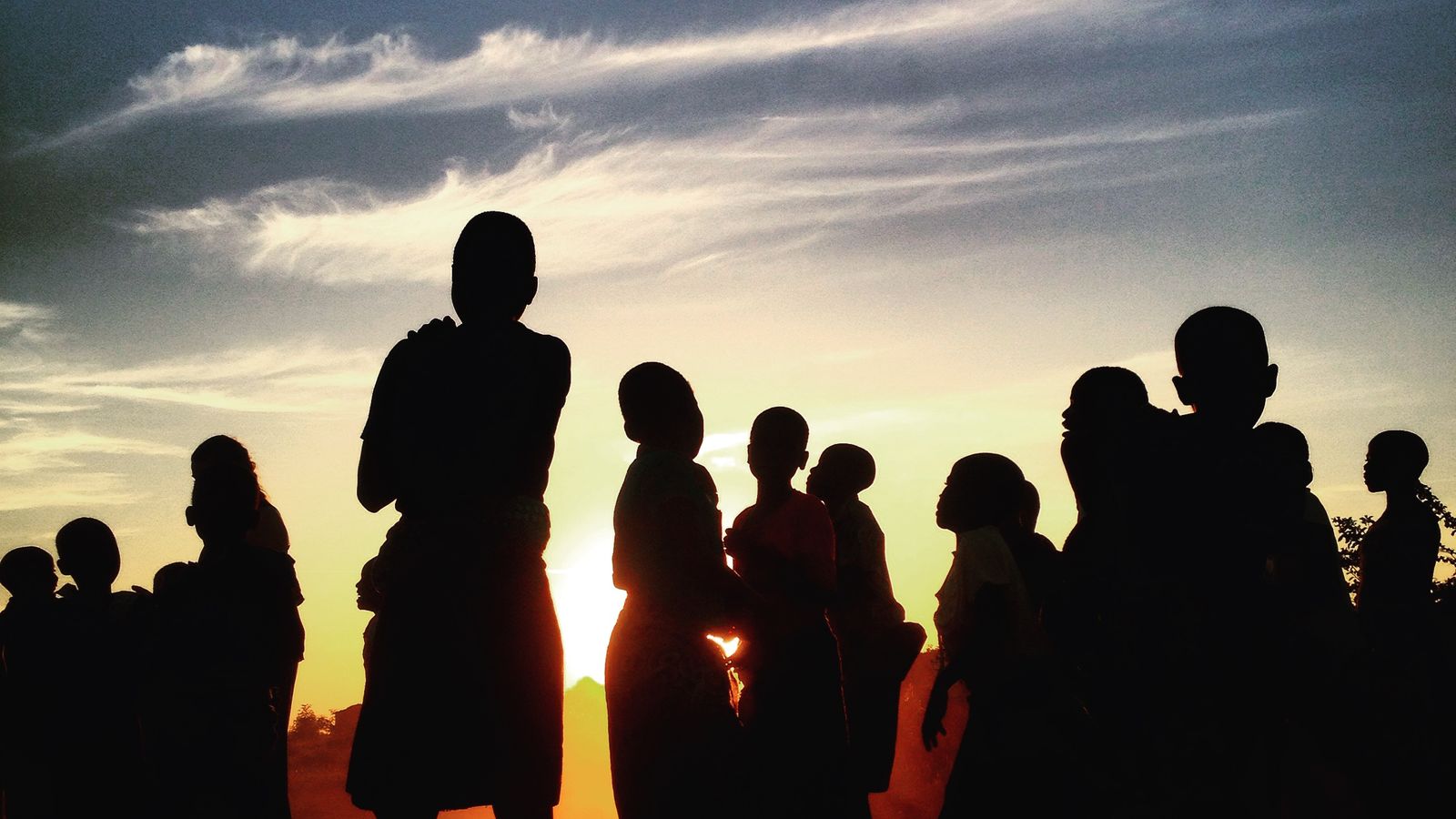 Silhouettes d'un groupe de personnes se détachant sur un ciel de coucher de soleil.