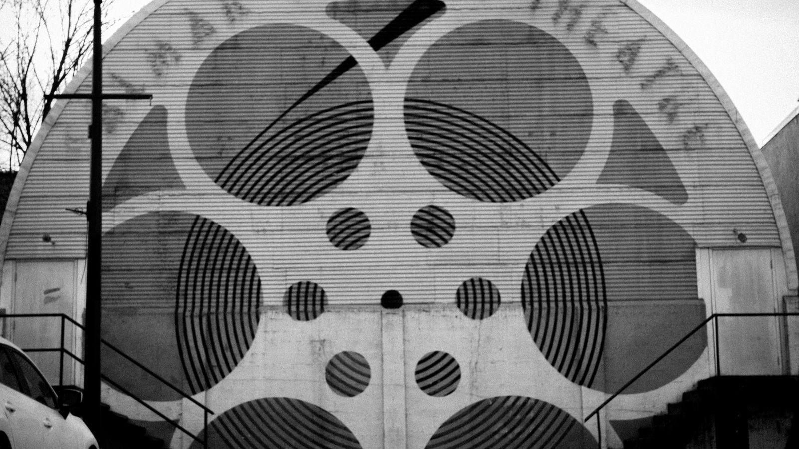 Façade en noir et blanc d'un cinéma classique, motif de pellicule de film sur le fronton.