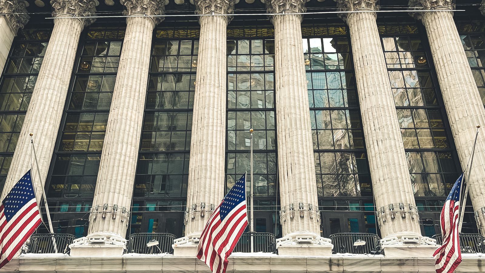 Façade à colonnades de la Bourse de New York, drapeaux américains au premier plan.
