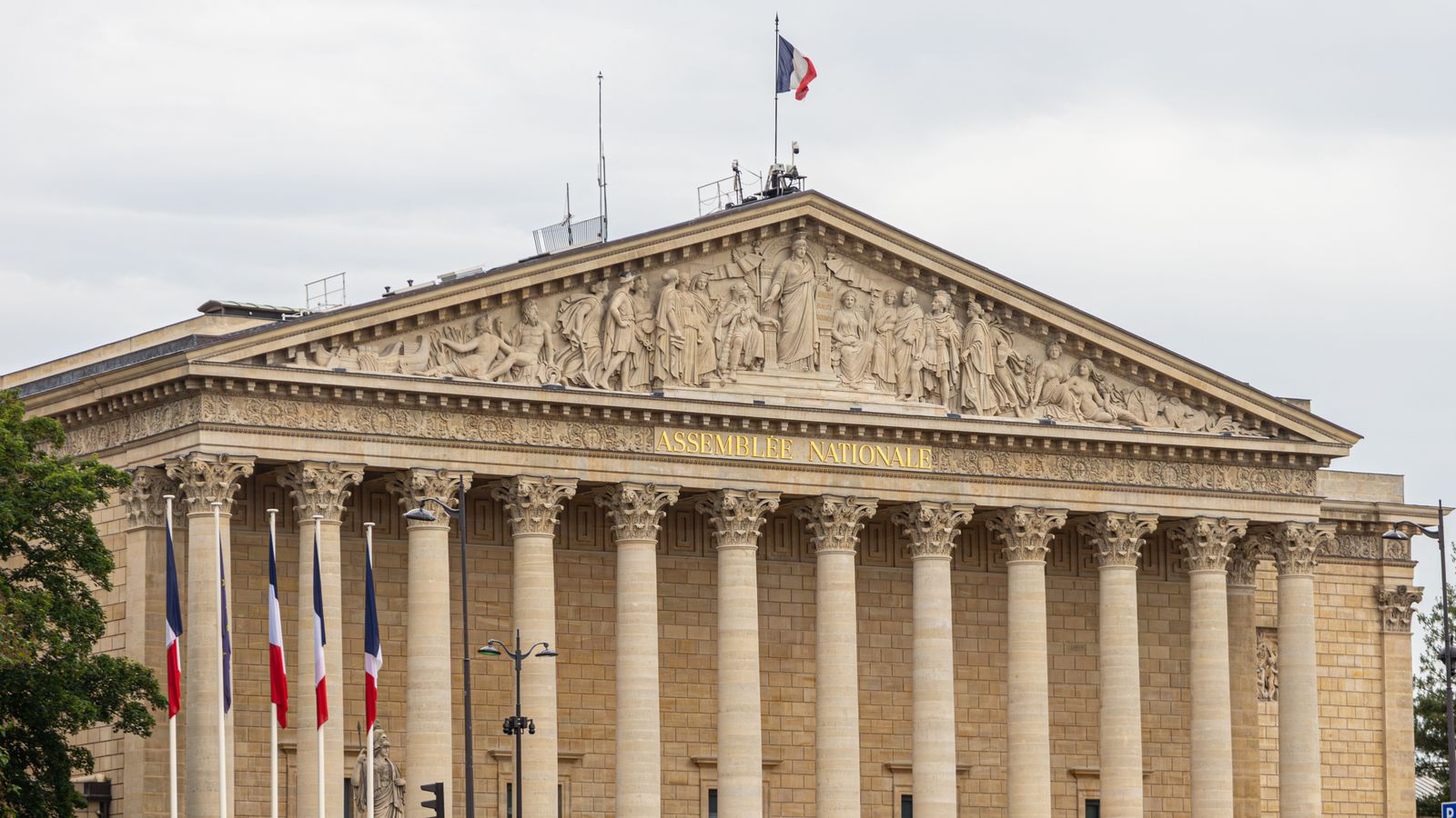 La façade de l'Assemblée nationale, à Paris, drapeaux français au vent.