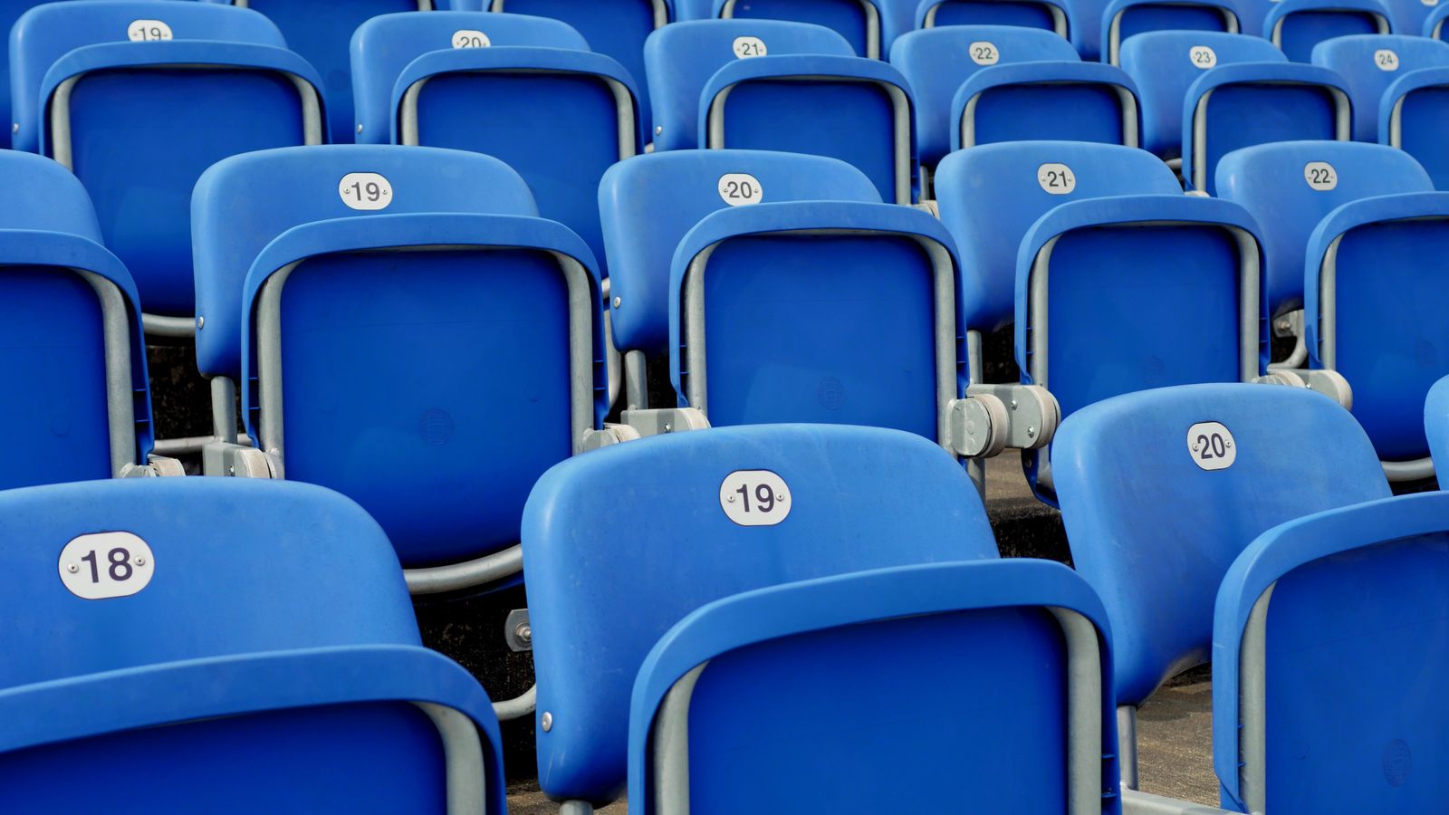 Rangées de sièges bleus vides dans un stade de football.